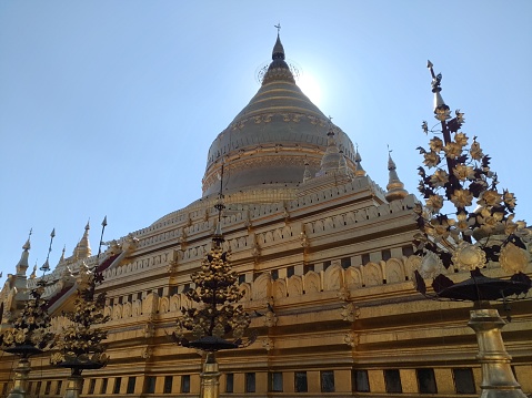 Yangon, Myanmar - January 15, 2020 : The golden Shwezigon pagoda, a Buddhist temple in Nyaung U near Bagan, glows in late afternoon light against the blue sky. Its construction began during the reign of King Anawratha (1044–77) and was completed by his son King Kyanzittha.