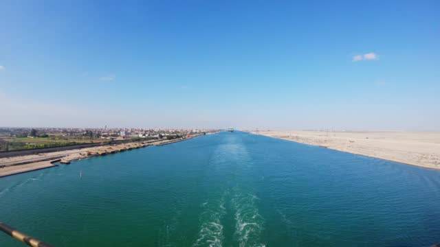 Timelapse of a vessel sailing through Suez Canal on a sunny day in the desert.