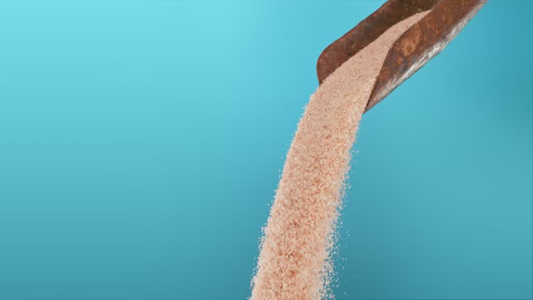 Super slow motion pile of brown ground sugar falling from a metal scoop