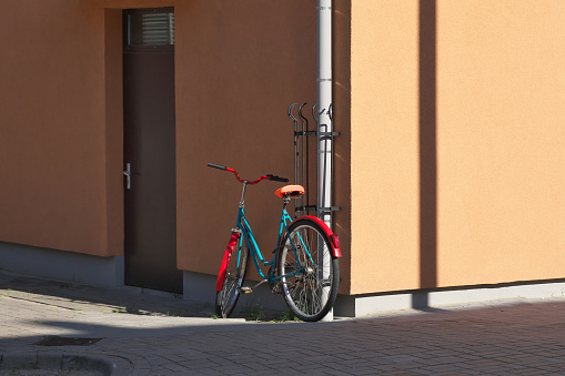 A red and blue bicycle by a pink building.