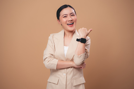 Asian woman happy smiling showing copy space for advertising standing isolated on beige background.