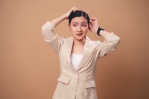 Asian woman worried confused, thinking about problem, standing isolated on beige background.