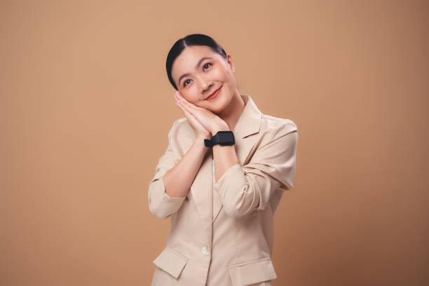 istock Asian woman making sleep gesture, isolated on beige background. 1999664079