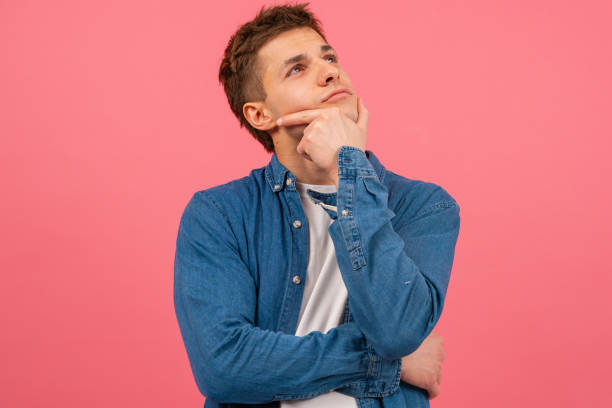 istock Portrait Thoughtful young man on pink background 1999664493