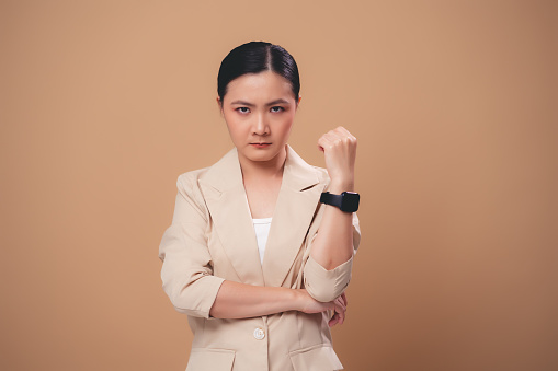 Asian woman angry standing isolated on beige background.