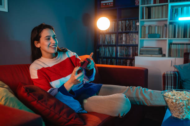 istock Young woman playing video games at home 1999705770
