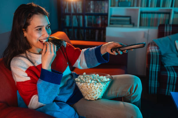 istock Young woman watching TV at night 1999705782