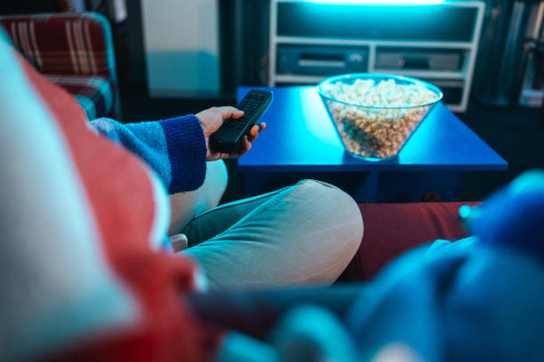 istock Unrecognizable woman watching TV and eating popcorn 1999706843