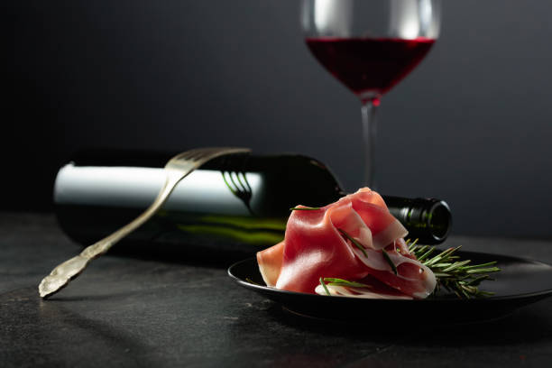 istock Prosciutto with rosemary and red wine on a black background. 1999737280