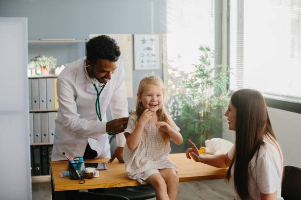 istock Mother and child seeing family practitioner. Smiling pediatrician with stethoscope checking little girl's lungs. 1999783206