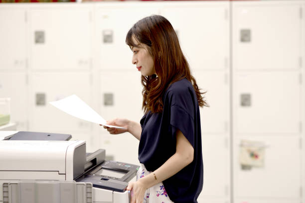 Close up hand of woman press start copy button on photocopier.