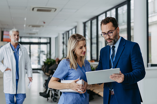 Pharmaceutical sales representative presenting new product to doctors in holding box with pills. Presenting new pharmaceutical product, drugs, medication.Hospital director, manager in private medical clinic showing something on tablet.