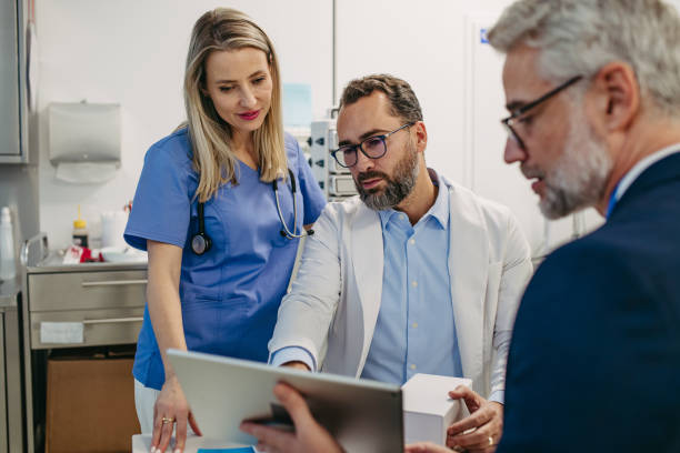 istock Pharmaceutical sales representative talking with doctors in medical building, presenting new product on tablet. 1999860470