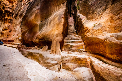 Steps carved in red sandstone rocks in narrow path of Petra, Jordan