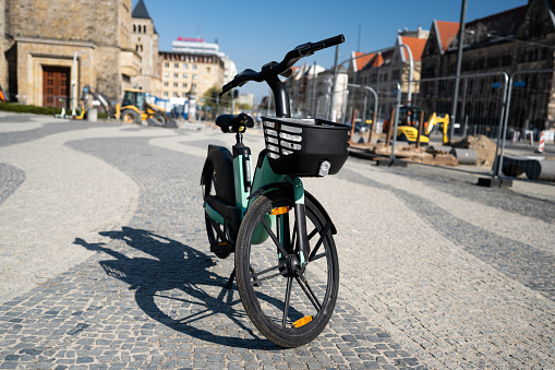 Electric City Bike With Product Basket Stands Ready For Use On A Bustling City Street