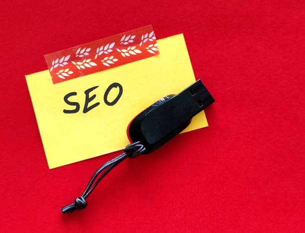 On copy space red background, flash drive with handwritten note SEO, refers to Search Engine Optimization - process of optimizing web pages and content to be easily discoverable by users