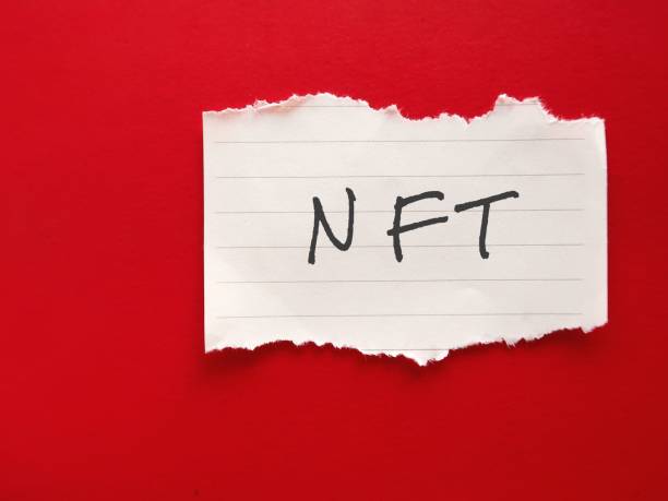 istock Torn paper on red background with handwritten  NFT - (Non-fungible token) digital object like drawing, animation, music, photo, video with certificate of authenticity created by blockchain technology 1999906221