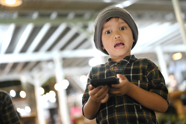 Close-up portrait of surprised boy while using phone at night