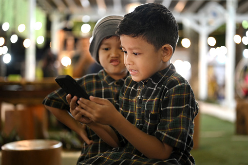Two young boys watching smartphone at night