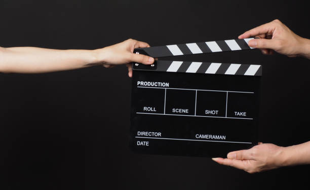 istock Hands send and hold Black clapper board or movie slate on black background. 1999928345