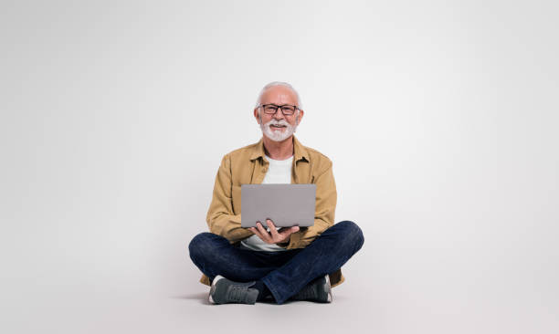 istock Confident senior male professional checking e-mails over laptop while sitting on white background 1999928471