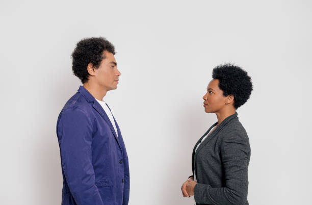istock Side view of serious young business coworkers facing each other while standing over white background 1999928545
