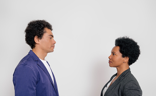 Side view of businessman and businesswoman confronting each other while standing on white background