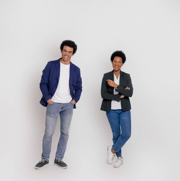 istock Full length of confident partners smiling and looking at camera while standing on white background 1999928604