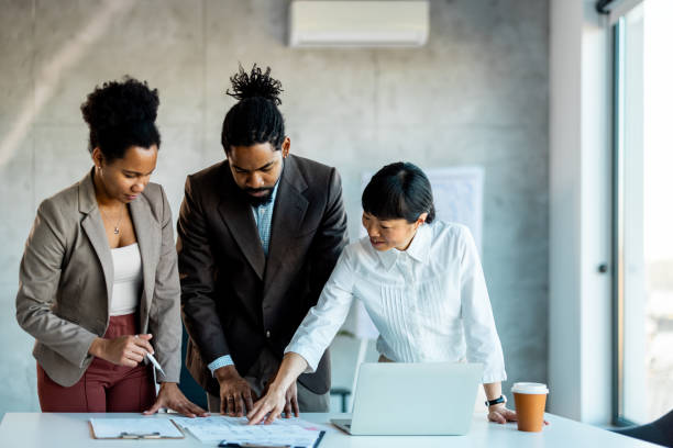 istock Multi racial diverse group of people working with Paperwork on a board room table at a business presentation or seminar. 1999929176