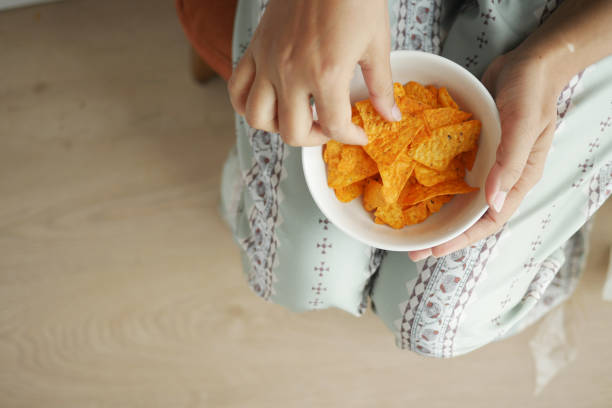 istock top view of woman eating potato chips. 1999931407