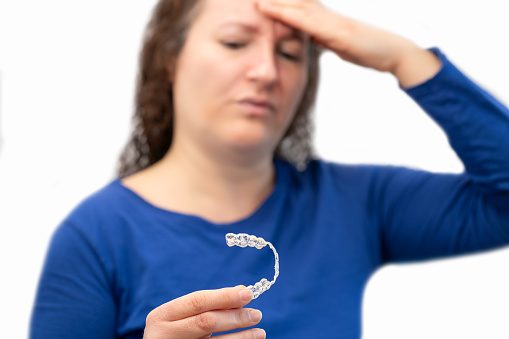 Close up of a worried woman hand holding her worn and broken silicone trainer with white background