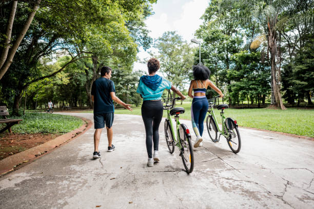 istock Friends walking and pushing bicycles in the park 1999951674