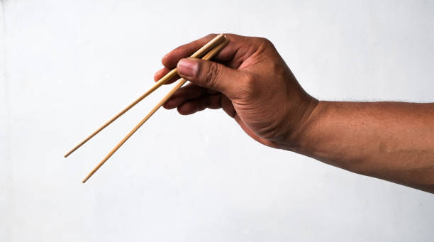 istock man's hand holding chopsticks isolated white background 1999966130