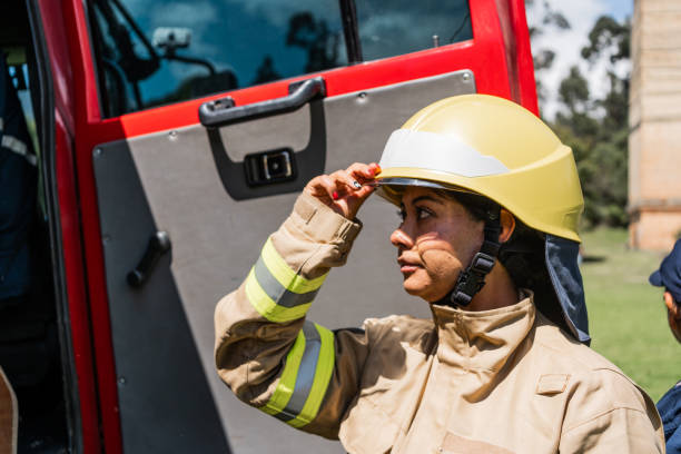 Mid adult firefighter woman getting dressed on fire truck