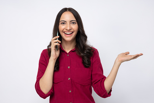 Portrait of young cheerful amazed girl wearing shirt talking on phone isolated over white background