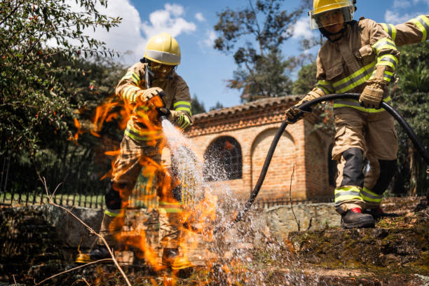 Firefighters using hose to put out fire outdoors