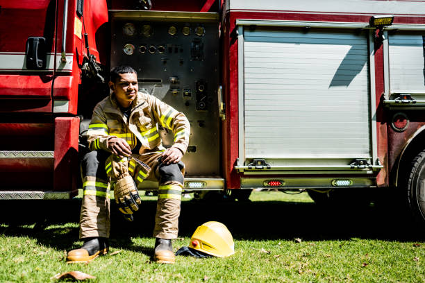 istock Young fireman sitting on fire truck outdoors 1999984942