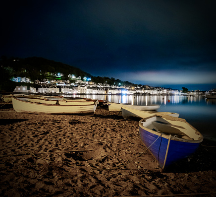 The boats resting on the sandy beach under moonlight near tranquil waters. Teignmouth, England