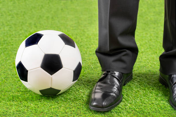 Close up of coach standing next to soccer ball on field