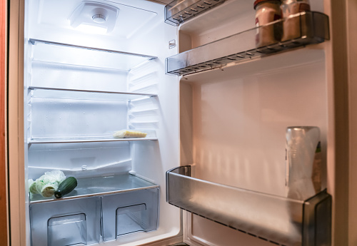 Almost empty  fridge with open door Surrey England