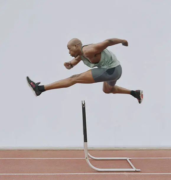 Photo of Man jumping hurdle, side view