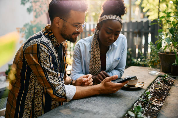 istock Young multiracial couple using mobile phone while sitting in a cafe, 2000106787