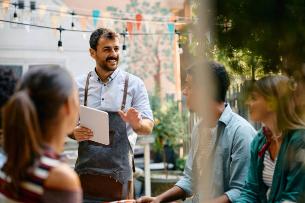 istock Happy waiter taking order from group of young people in a cafe. 2000108466