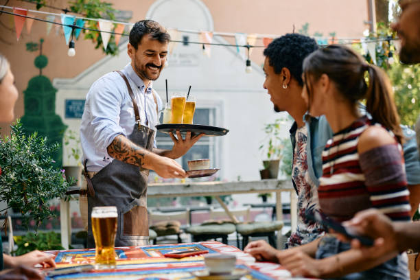 istock Happy waiter serving drinks to group of guests in a cafe. 2000110088