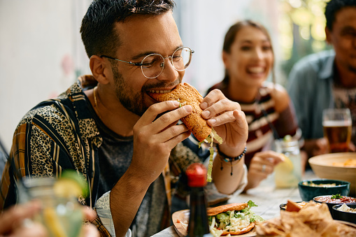 Young man eating tacos during a lunch with friends in Mexican restaurant.