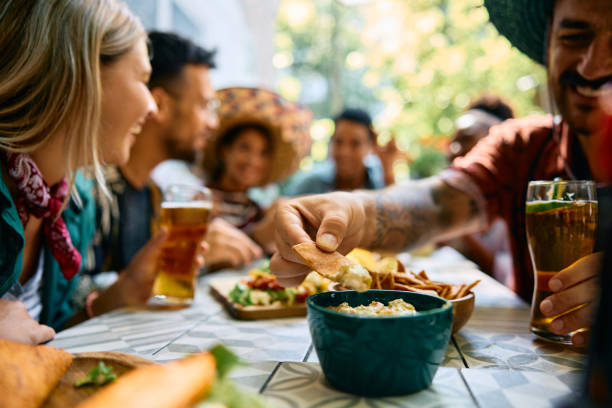 istock Close up of man dipping nacho chips in guacamole. 2000118708