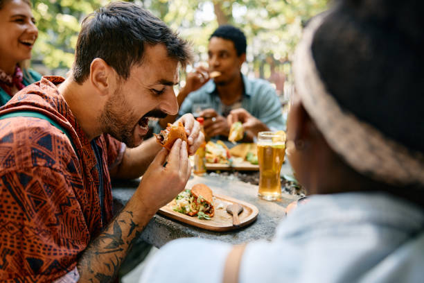 istock Hungry man eating tacos while gathering with friends for a lunch in restaurant. 2000124668
