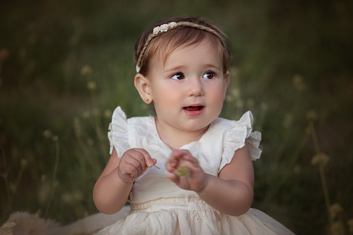 Funny little princess girl in silver crown and pink dress over blue background