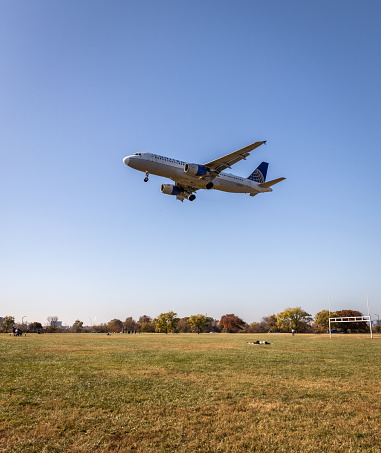 Arlington, United States – November 13, 2023: A United Airlines plane flying over a park in Arlington before landing at Ronald Reagan Airport