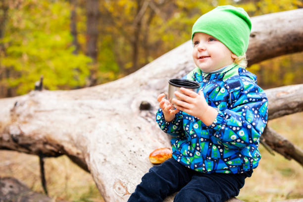 Smiling child with a cup, resting during an autumn hike
